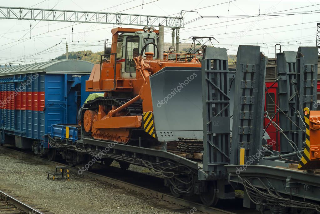 heavy orange bulldozer stands on the flatcar of the train for accident recovery work