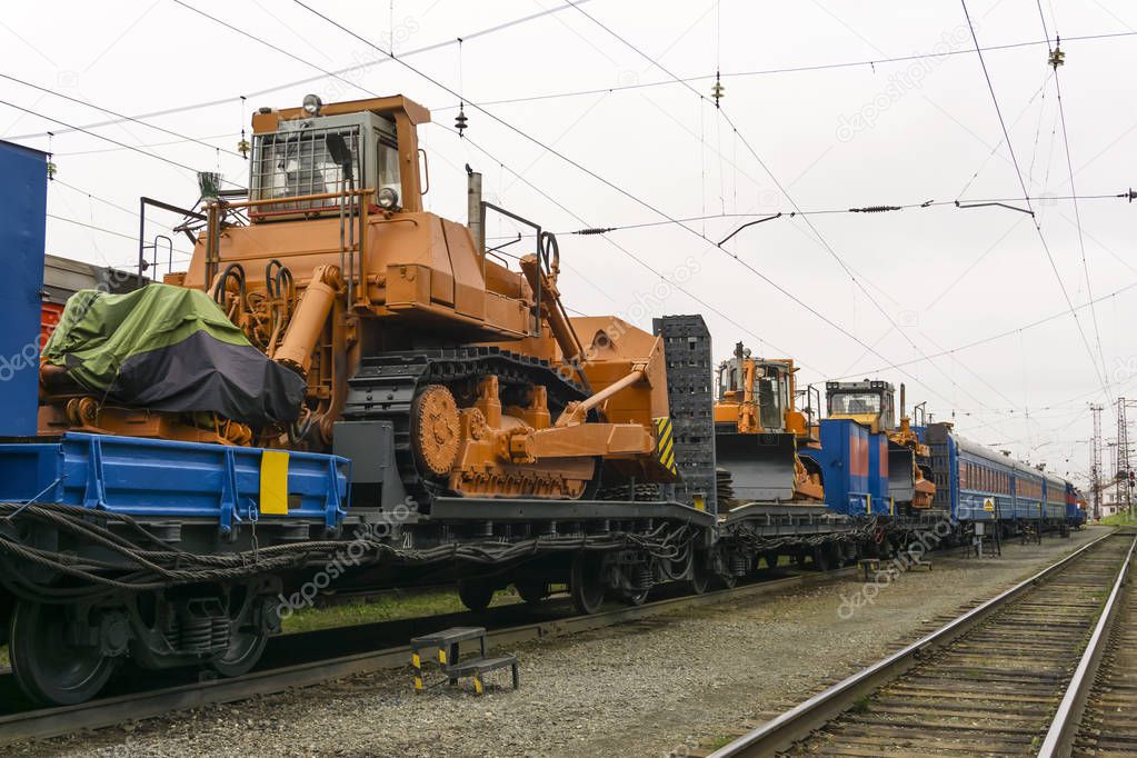 heavy orange bulldozers stands on the flatcar of the train for accident recovery work