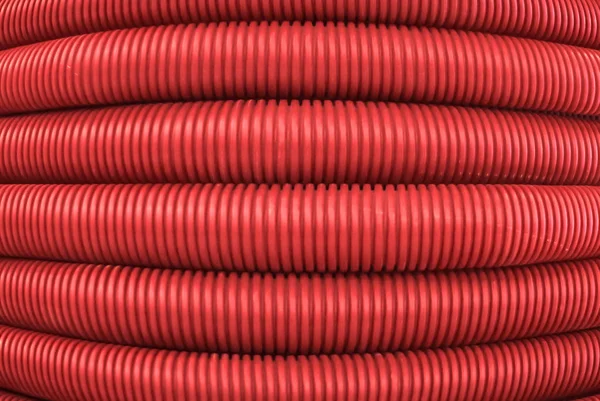 background - red corrugated flexible polymer tubes close up