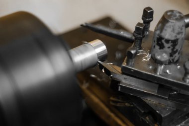 turning a rotating workpiece on a old manual metalworking lathe, focus on the tip of the tool bit clipart