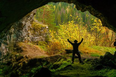 Sonbahar dağ manzara outsid zemin karşı mağara keşfetmek üzerine araştırmacı elinde jeolojik çekiçle sevinir