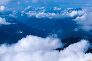 yukarıdan, tepe veya bir uçak, yerleşim, kısmen kümülüs bulutu tarafından gizli bir ormanlık dağ Vadisi için göster