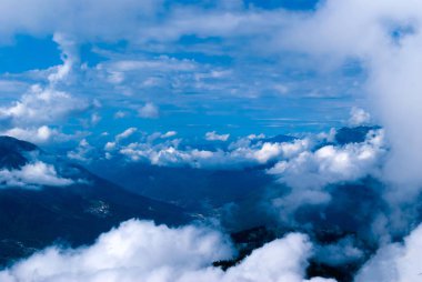 yukarıdan, tepe veya bir uçak, yerleşim, kısmen kümülüs bulutlar tarafından gizli bir ormanlık dağ Vadisi için göster