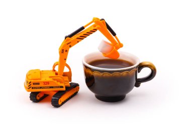 oyuncak Ekskavatör gerçek bir fincan kahve hafif bir arka plan üzerinde küp şeker yükler