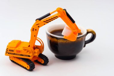 oyuncak Ekskavatör gerçek bir fincan kahve hafif bir arka plan üzerinde küp şeker yükler