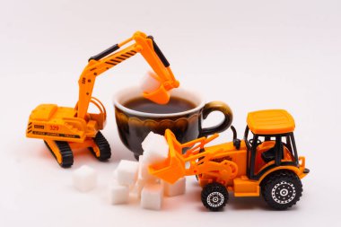 Oyuncak İnşaat makineleri yükler şeker içine gerçek bir fincan kahve hafif bir arka plan üzerinde