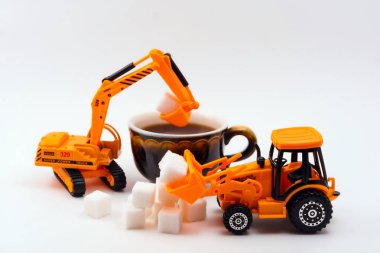 Oyuncak İnşaat makineleri yükler şeker içine gerçek bir fincan kahve hafif bir arka plan üzerinde