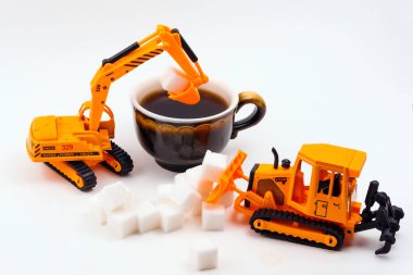 Oyuncak İnşaat makineleri yükler şeker içine gerçek bir fincan kahve hafif bir arka plan üzerinde