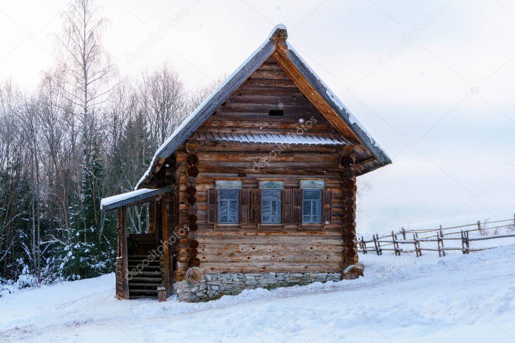 old log Russian peasant hut izba in the winter landscape