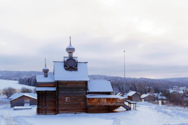 ancient russian wooden log village orthodox church in winter landscape clipart