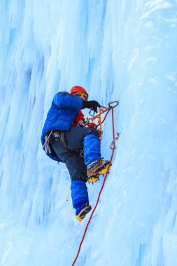 buz tırmanıcı bir dikey blue Ice duvar bir kar yağışı sırasında tırmanıyor.
