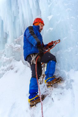 buz dağcı Tırmanıştan önce buz vida ile çapa güvenilirliğini denetler, ipi tarafından carabiner yakalar