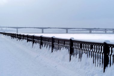 Kış manzarası - bir donmuş nehir yolu köprüsü mesafe ve akşam Parmaklığa dökme demir dolgu ile karlı gökyüzü bulutlu.