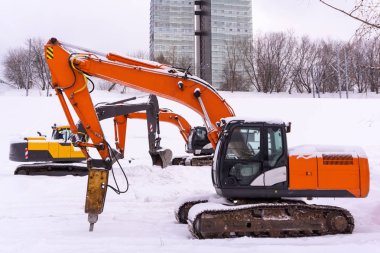 Üç renkli Zincirli ekskavatör karlı bir alan üzerinde park edilmiş, booms ve form bir enfilade sopa