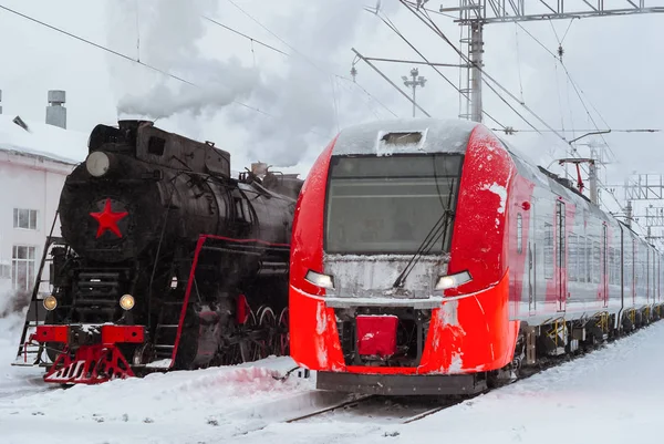 Locomotiva a vapor e moderno trem de várias unidades estão nas proximidades em — Fotografia de Stock