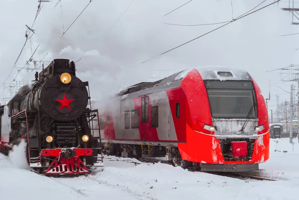 Locomotiva a vapor e moderno trem de várias unidades estão nas proximidades em — Fotografia de Stock