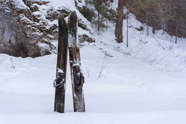 artisanal old broken skis stuck in the snow against the backdrop