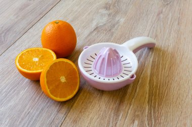 two oranges and juice reamer on wooden table clipart