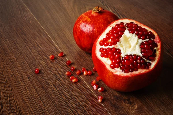 Red pomegranate fruits and seeds on a dark surface — Stock Photo, Image