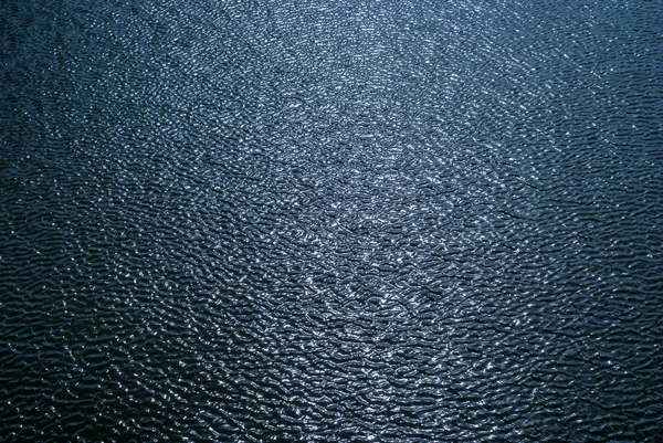 Фон - глянсова поверхня води з хвилями та відображенням неба — стокове фото