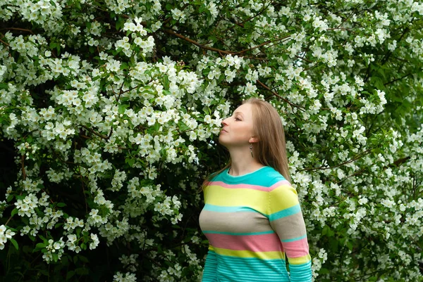 Dziewczyna uśmiechnięta wąchania kwiaty jabłoni — Zdjęcie stockowe