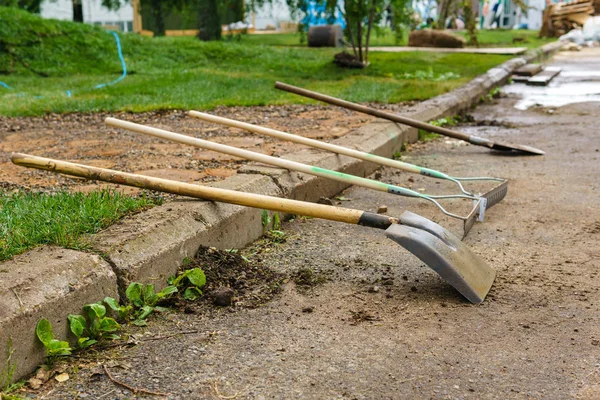 Garden tools are lying on the curb on the background of the site — Stock Photo, Image