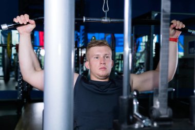 Genç adam bir Weig kullanarak omuz kemeri kasları trenler