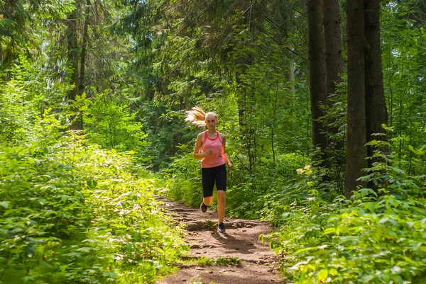 Jonge vrouw joggen in een berg woud — Stockfoto