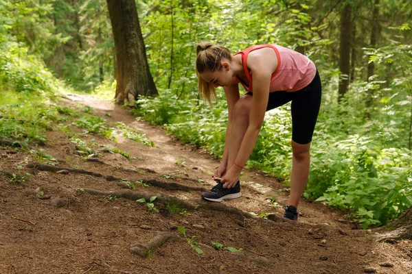 Vrouw stopte met joggen in een berg woud om schoenveters te binden — Stockfoto