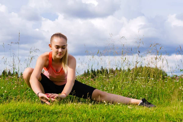 Jeune femme faisant des exercices étirant dans une prairie en dehors de la c — Photo