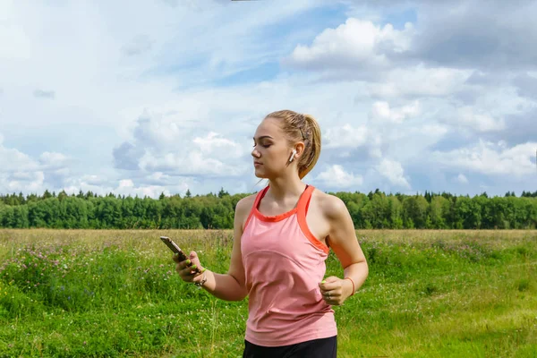 Jeune femme jogging dans la prairie et écouter de la musique sur la tête — Photo