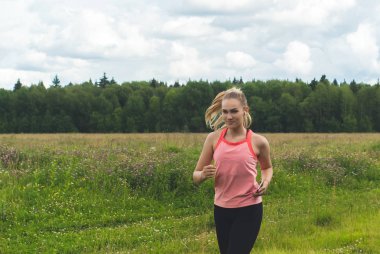 çayırda koşu ve baş müzik dinleyen genç kadın