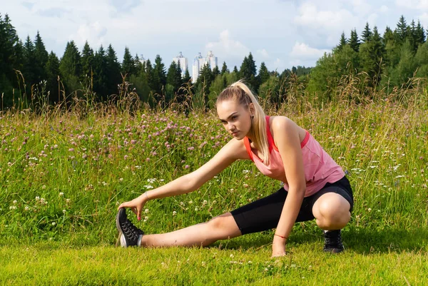 Jeune femme faisant des exercices étirant dans une prairie en dehors de la c — Photo