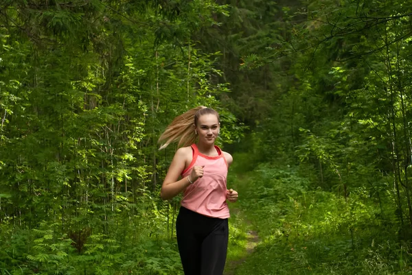 Jonge vrouw joggen in zonnig bos — Stockfoto