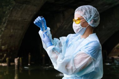 kadın ekolojist veya biyokimyager su f ile bir test tüpü inceler