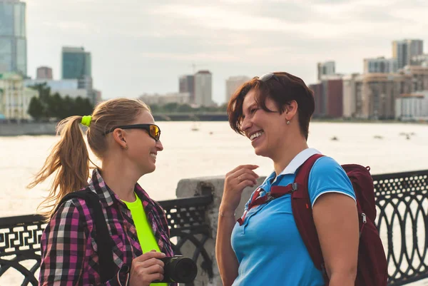 Dos mujeres turistas hablan y ríen en el paseo marítimo de la ciudad — Foto de Stock