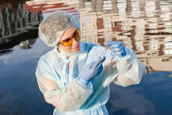 Epidemióloga femenina observa un tubo de ensayo con agua de una cit — Foto de Stock