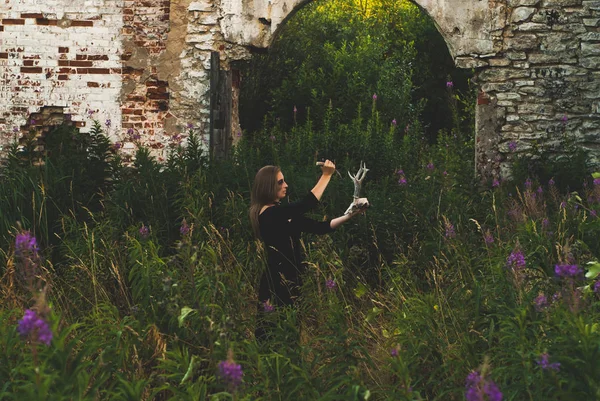女人扮演一个女巫进行一个不祥的仪式在废墟中 — 图库照片