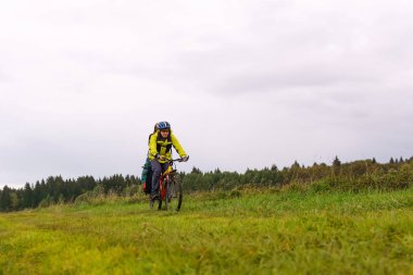 bisikletçi backpacker bir alan üzerinden bir toprak yolda sürmek