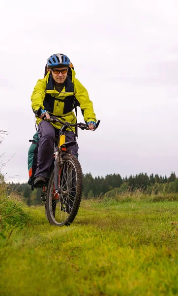 Cycling tourist on a dirt road through a field — Stock Photo, Image