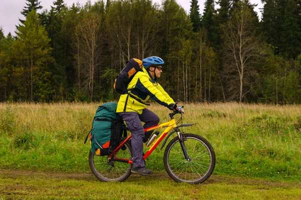 Cyklista jezdí po kraji lesa za zamračený den — Stock fotografie