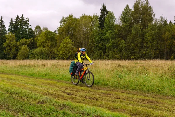 Ciclismo paseos turísticos en un camino de tierra a través de un campo —  Fotos de Stock