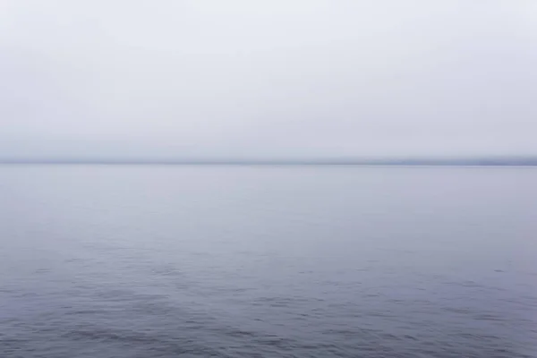 Studený vodní útvar se vzdáleným pobřežím skrytým mlhou — Stock fotografie