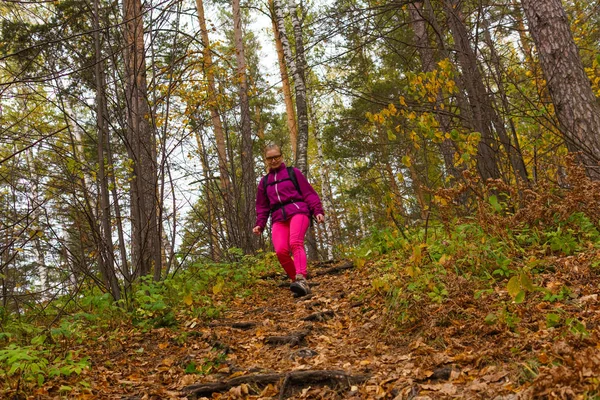 Vrouw reiziger daalt van een heuvel in het herfst bos — Stockfoto