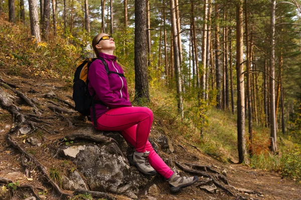 Втомлена жінка мандрівник сів відпочити на камінь і дивиться вгору — стокове фото