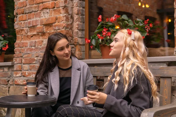 Kız kahve outd ile bir bankta arkadaşını dikkatle dinler — Stok fotoğraf