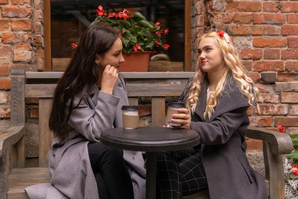 Two girls are drinking coffee on the street and talking — Stock Photo, Image