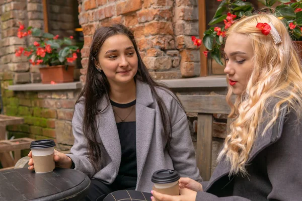 Dos chicas están tomando café en la calle y hablando — Foto de Stock