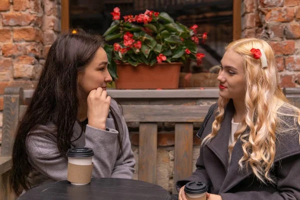 Two girls are drinking coffee on the street and talking — Stock Photo, Image