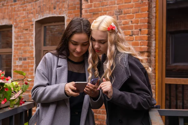 Dos chicas están viendo fotos en un teléfono inteligente — Foto de Stock